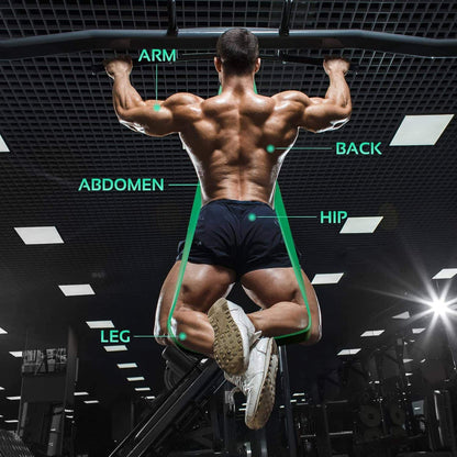 Muscular man in a gym with labeled body parts on a dark ceiling.