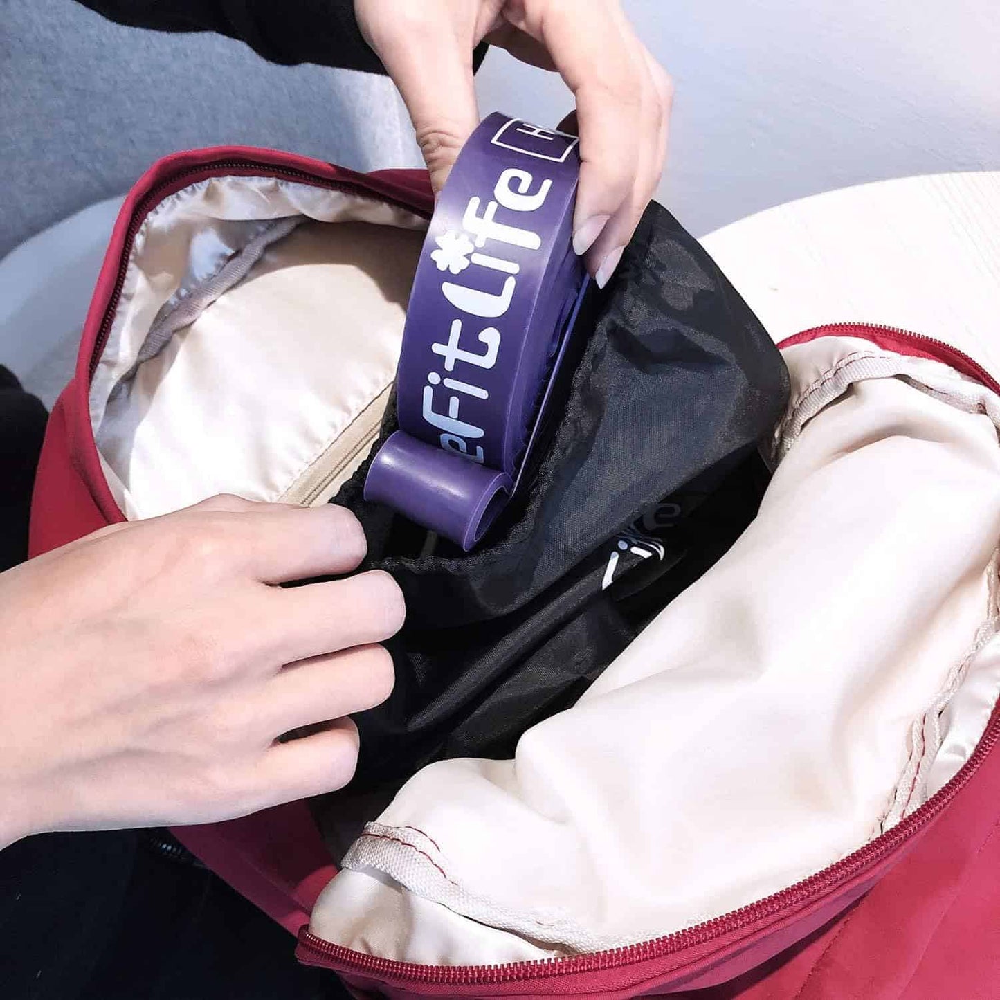 Person placing a purple 'Fit Life' product into a red bag.