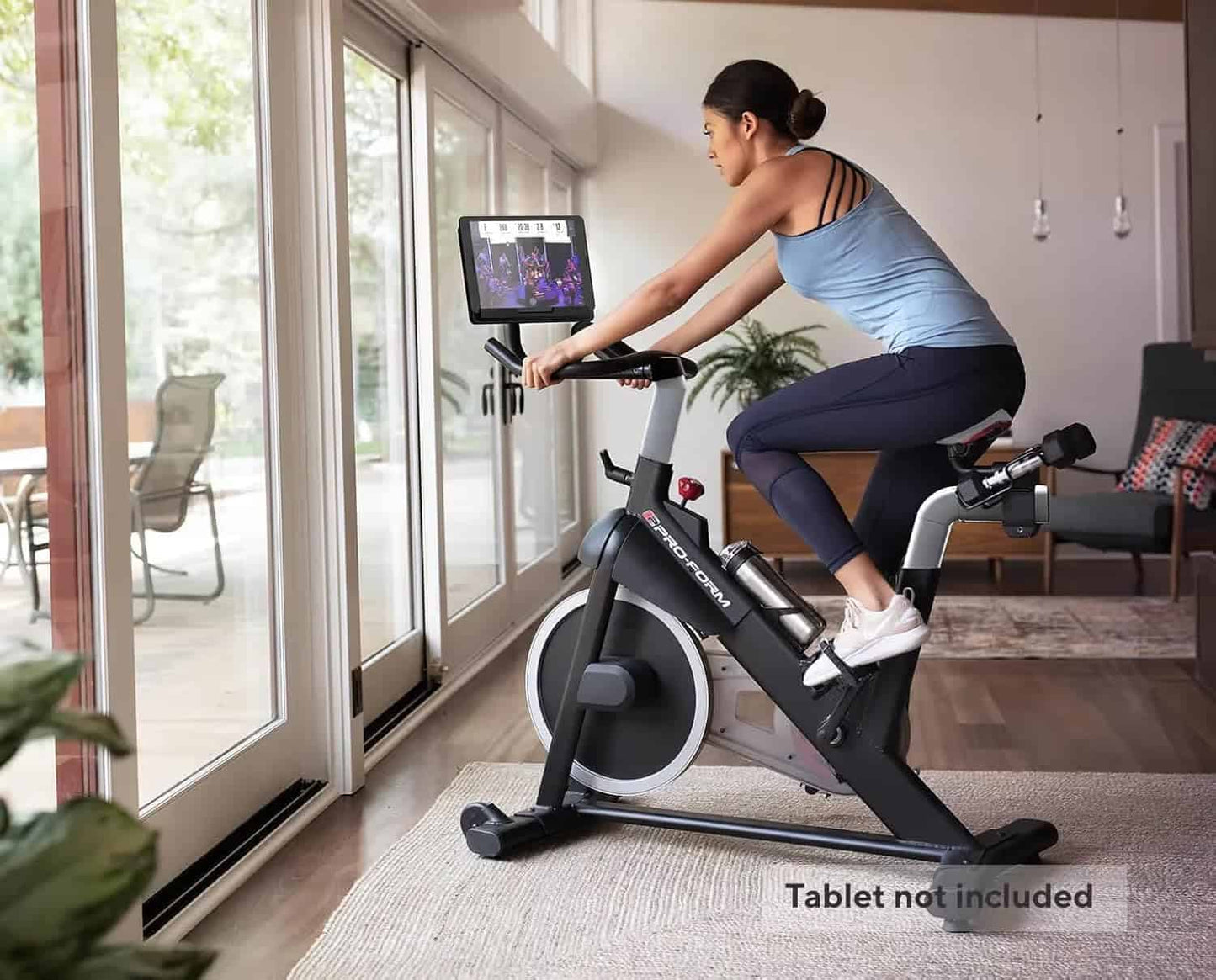 Person using a stationary bike in a home setting with a tablet attached to the bike.