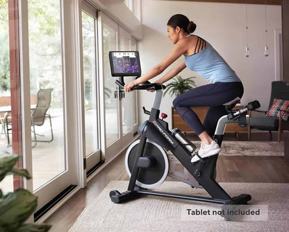 Person using a stationary bike in a home setting with a tablet attached to the bike.