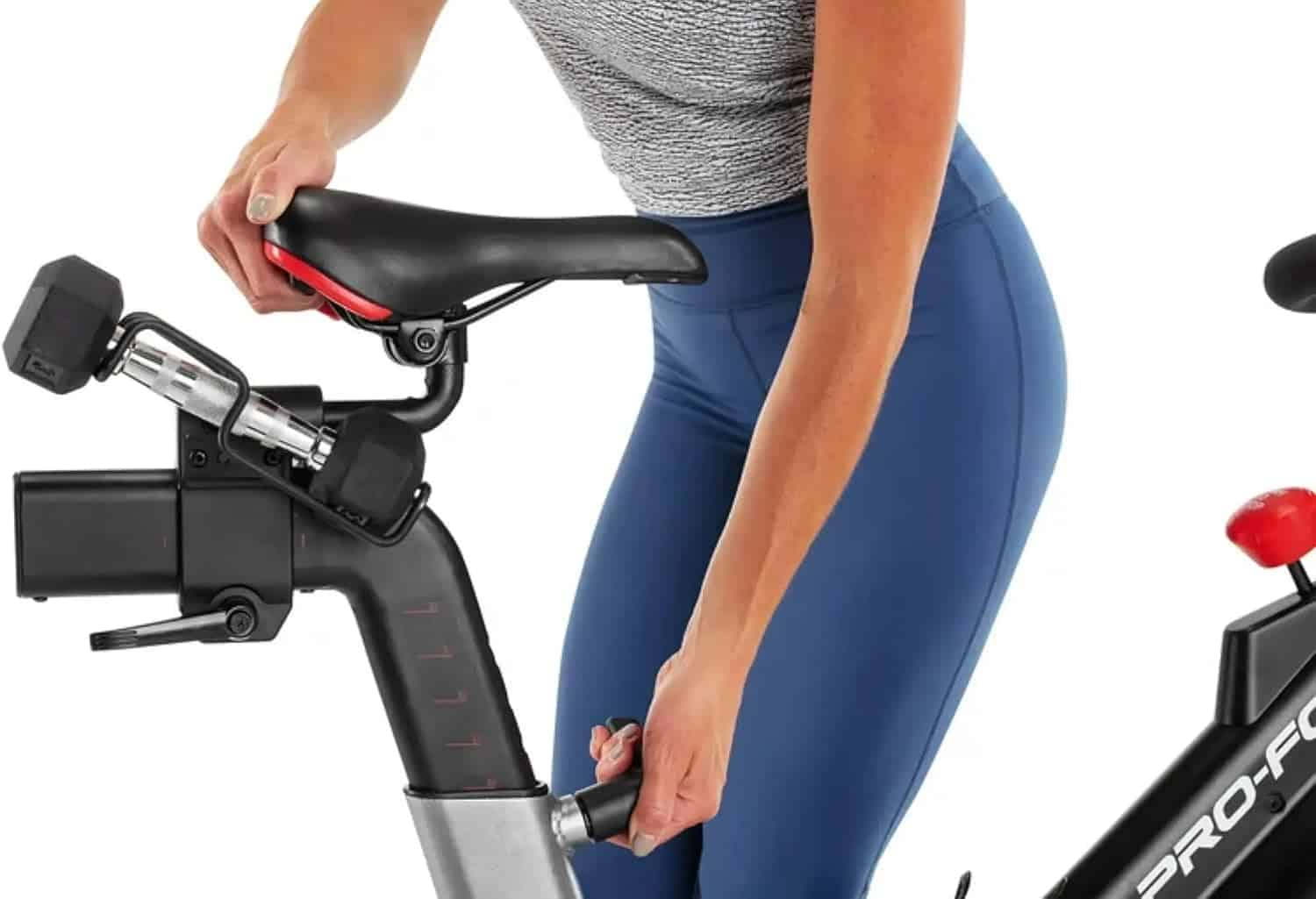 Person adjusting a stationary bike's seat on a white background
