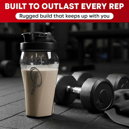 Shaker cup with protein powder next to dumbbells on a gym floor, with text about durability.